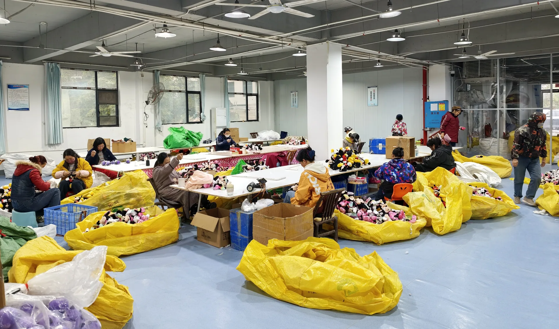 Workers assembling plush toys at production tables in a Chinese toy factory