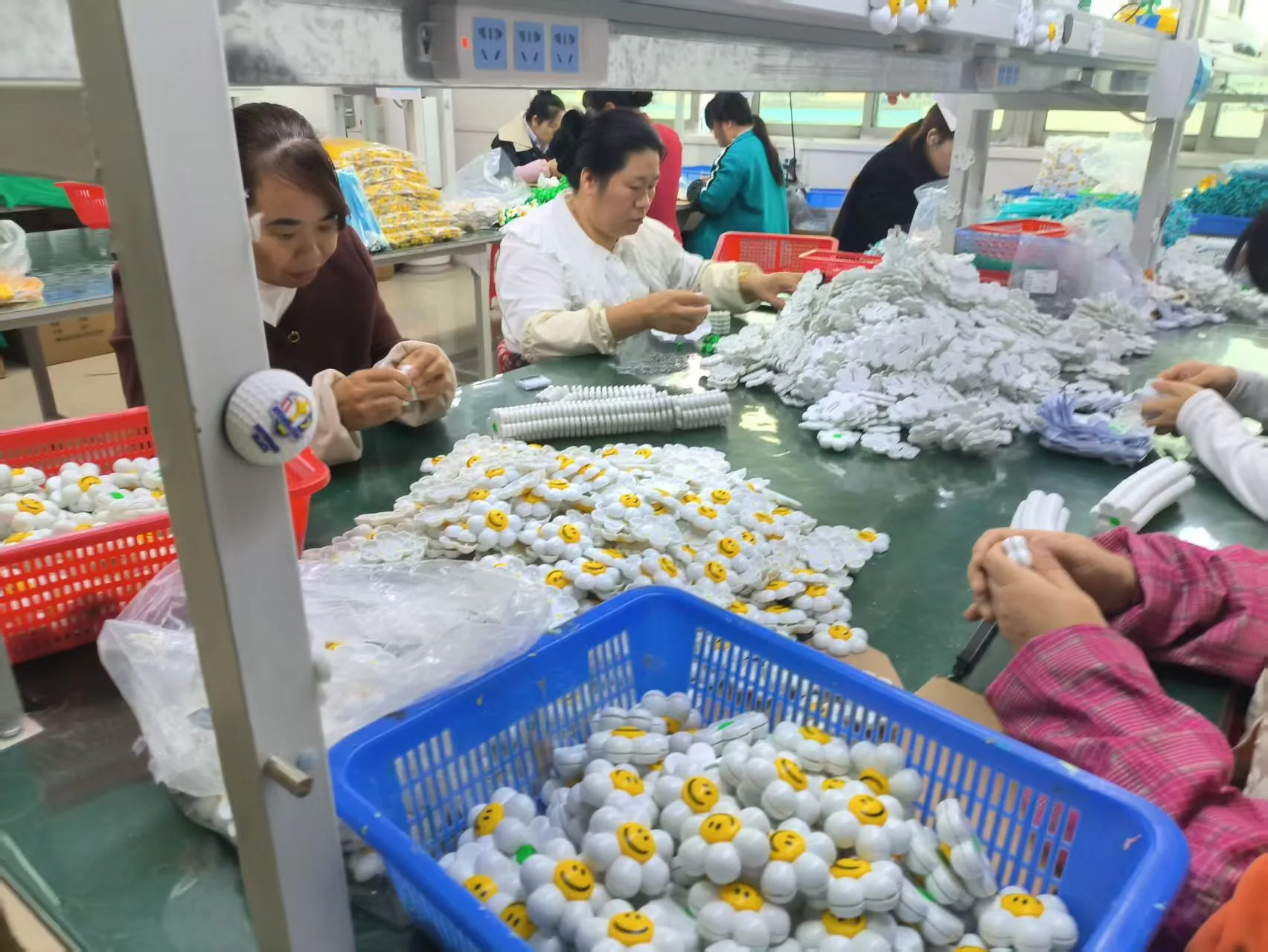 Workers assembling small parts at a production table